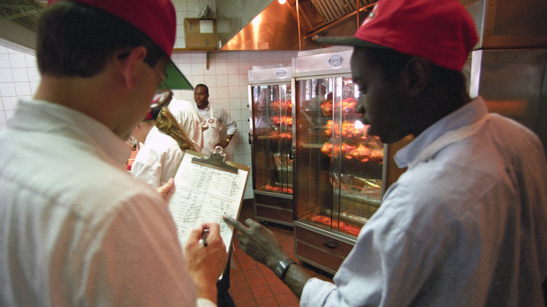 employees discuss rotisserie chickens in a store