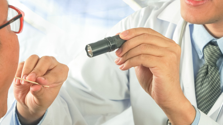 doctor shining light patient mouth