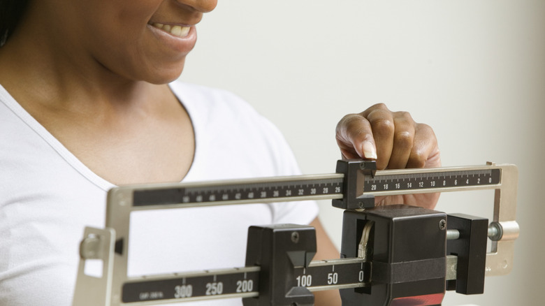 woman smiling as she learns her weight on a scale