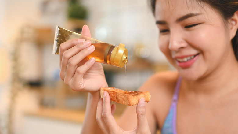 young adult woman putting honey on food