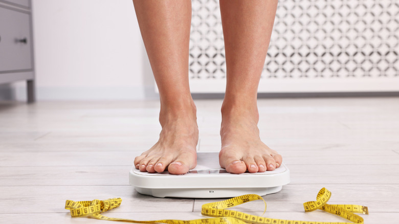woman weighing herself on a scale showing just feet