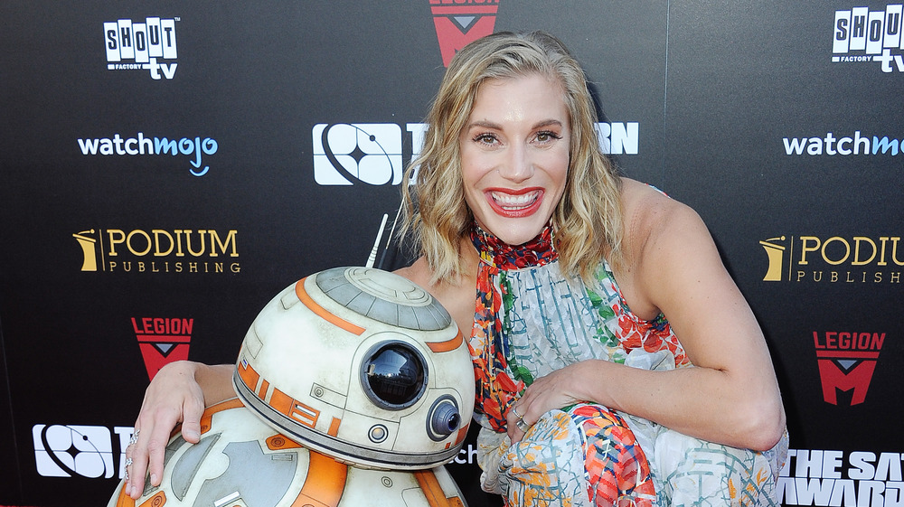 Katee Sackhoff posing on the red carpet with BB-8 from the Star Wars franchise