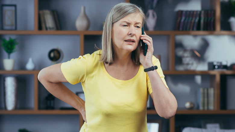 woman contacting doctor on phone about back pain