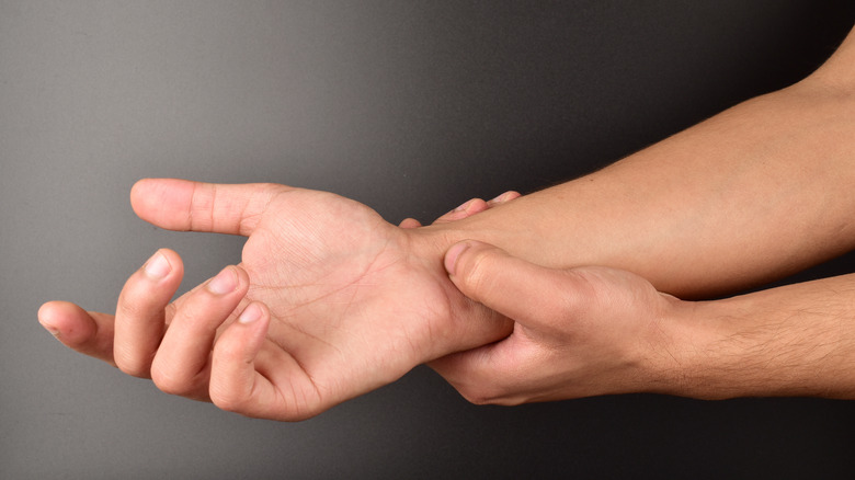 Man's hand doing acupressure on wrist