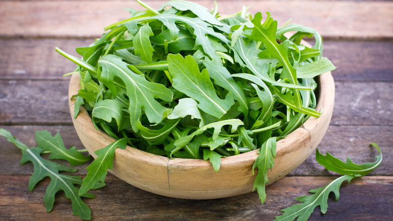 raw arugula in wooden bowl