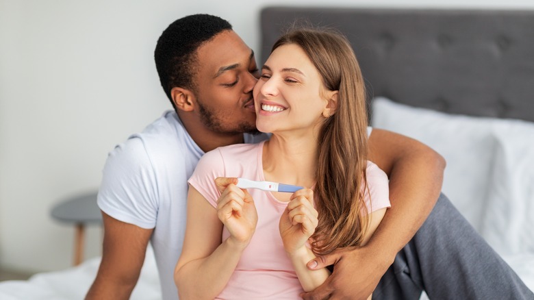 Embracing couple holding pregnancy test