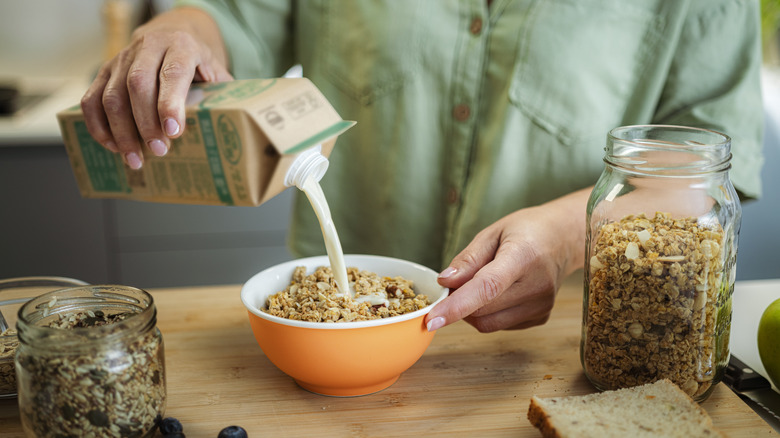 pouring boxed milk onto granola