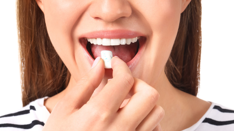 A woman eats a piece of chewing gum