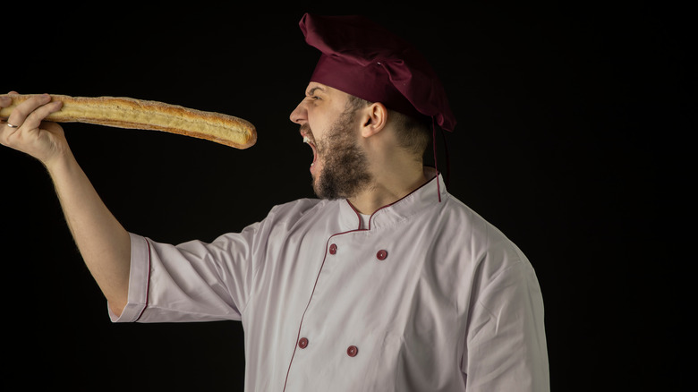 chef holds baguette up to his mouth