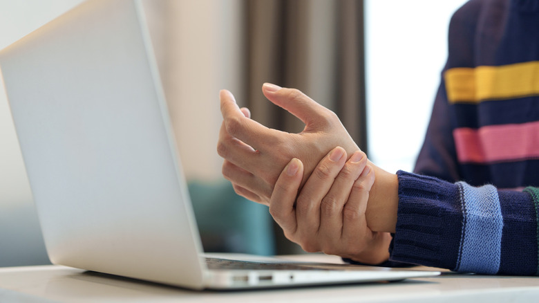 A hand holding a painful wrist due to carpal tunnel syndrome
