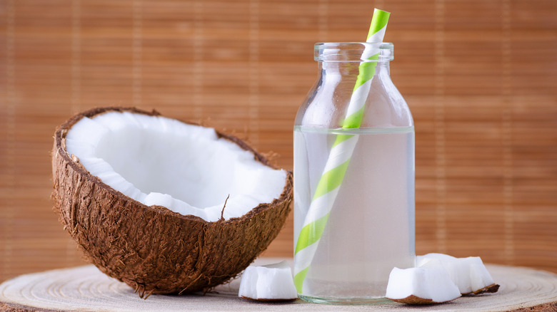 A bottle of coconut water next to a coconut