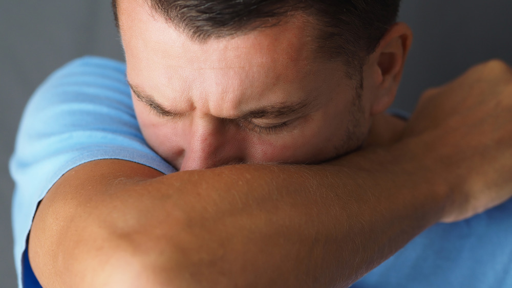 Man coughing into his elbow