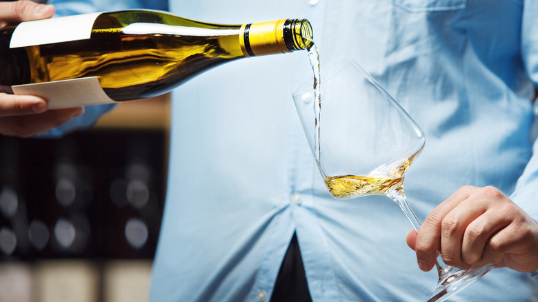 A man pouring white wine into a glass