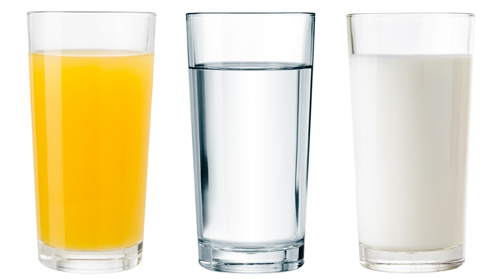 Water, milk, juice glasses on white background