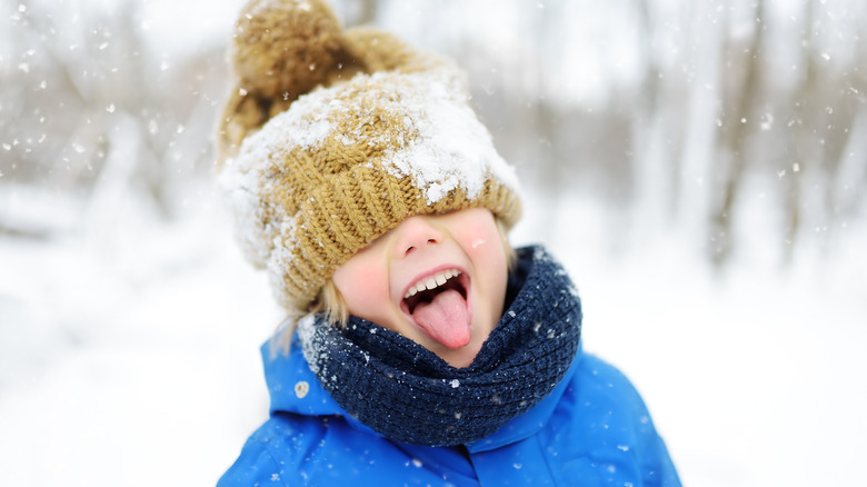 A little kid sticks his tongue out in a snow storm