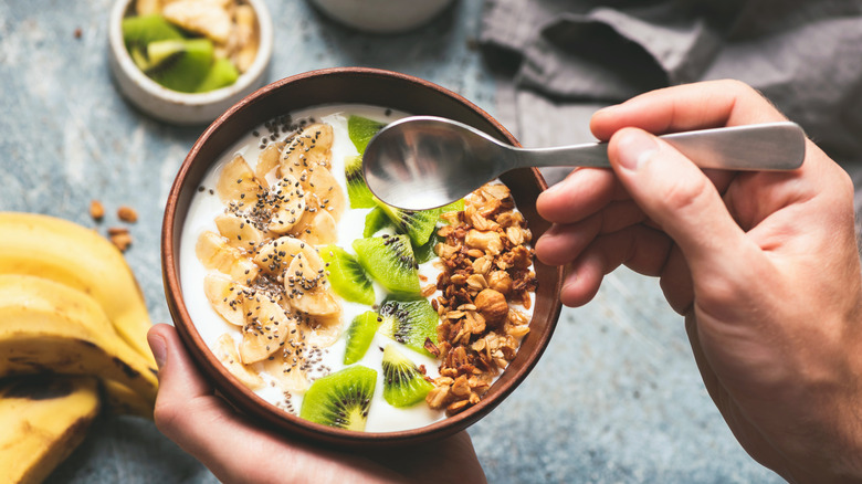 A bowl of yogurt with fruit and granola added. 
