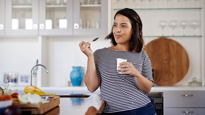 woman in her kitchen eating Greek yogurt