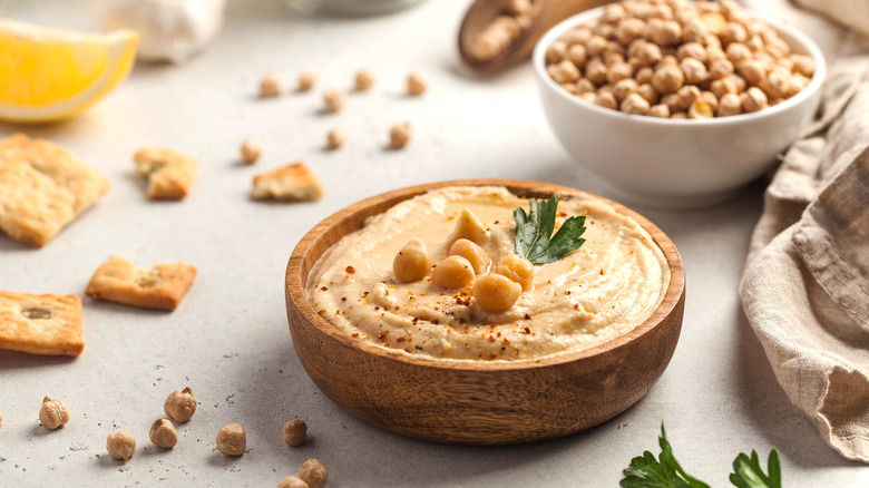 A bowl of hummus on a table with chickpeas on it