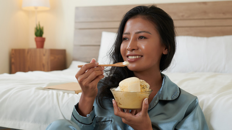 Smiling woman eating ice cream in pajamas