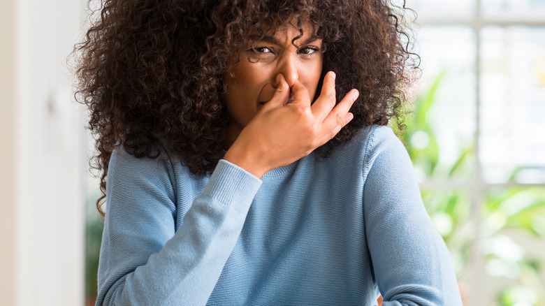 Woman closing nose against smell