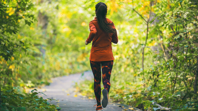 Woman running on outdoor path through the woods