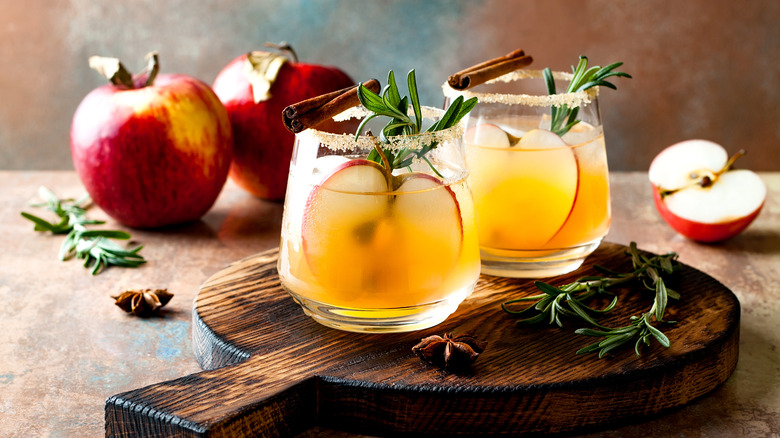 Decorative, spiced apple cider vinegar drinks on wooden cutting board