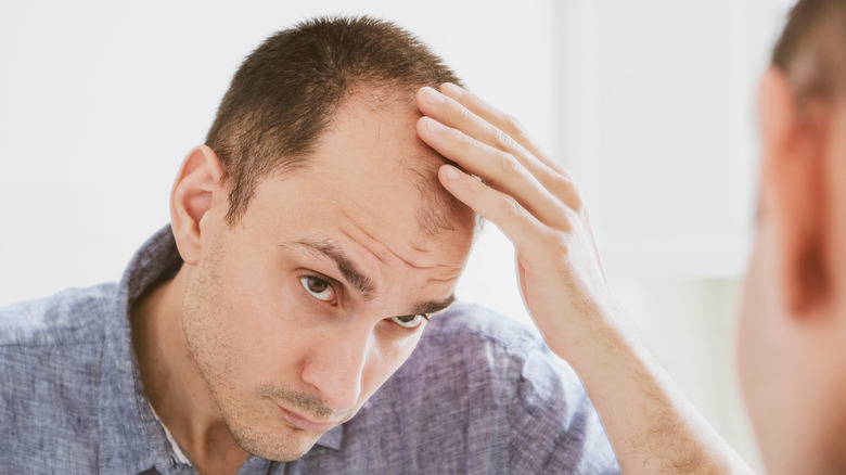 Man looking in mirror at balding 
