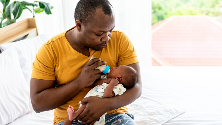 a dad feeding his newborn baby