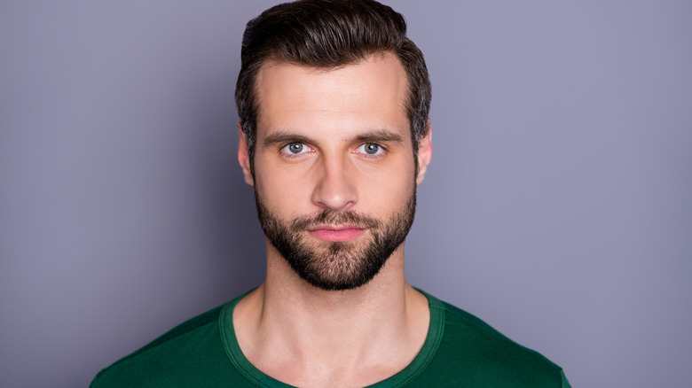 Man wearing green shirt against grayish background