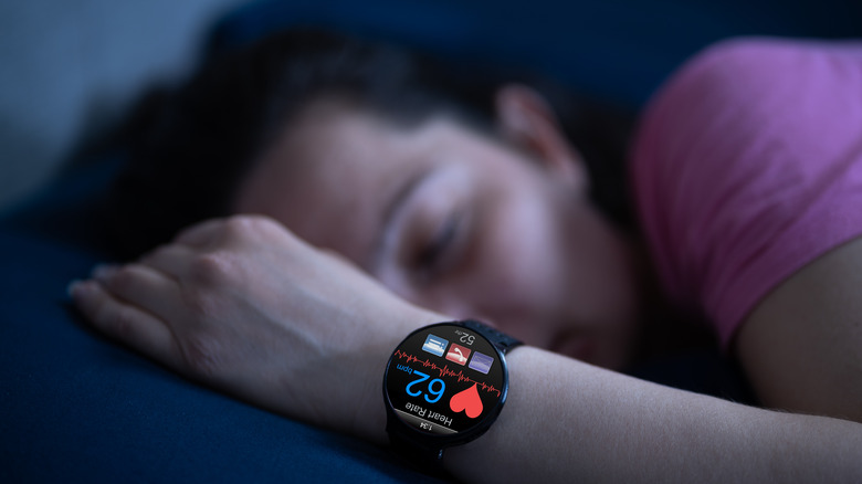 Person sleeping in bed with smartwatch on their wrist