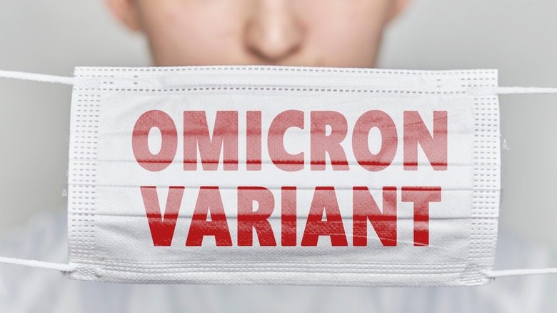 Person holding face mask with words 'Omicron Variant'