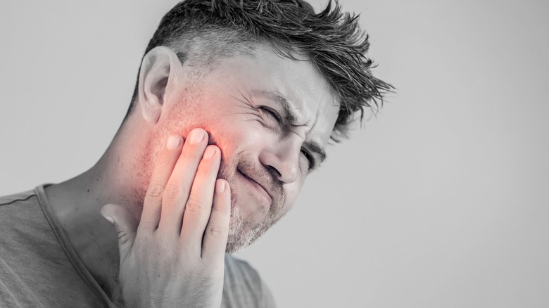 Man holding jaw in pain