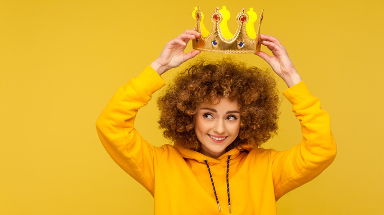 Young woman putting on a crown