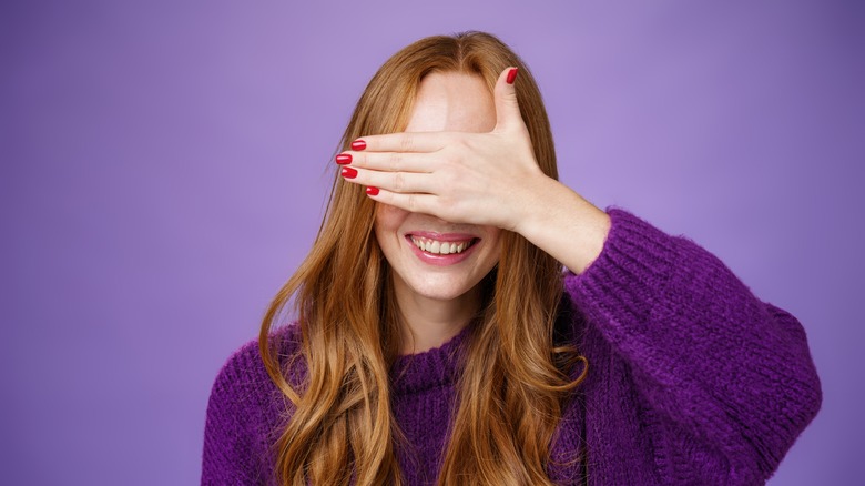 Woman wearing violet sweater covering eyes