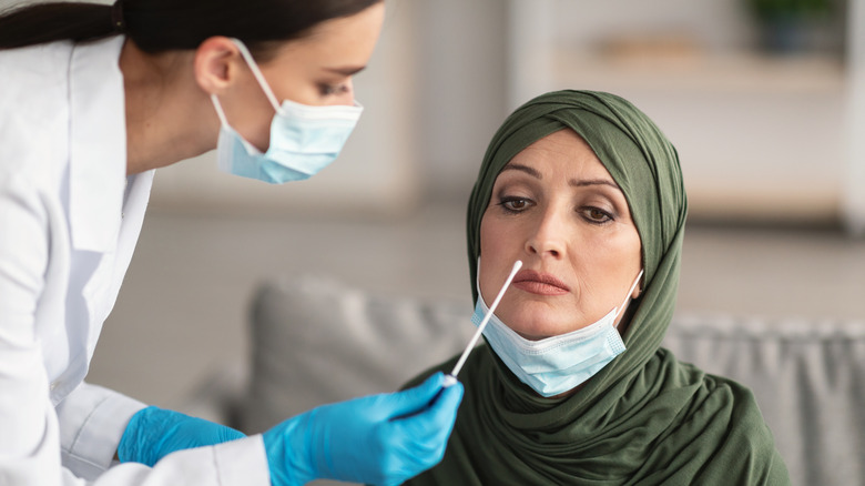 Masked doctor issuing PCR test