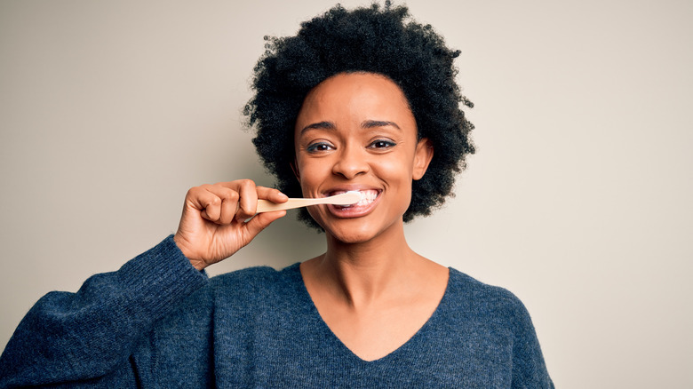 Woman smiling while brushing teeth