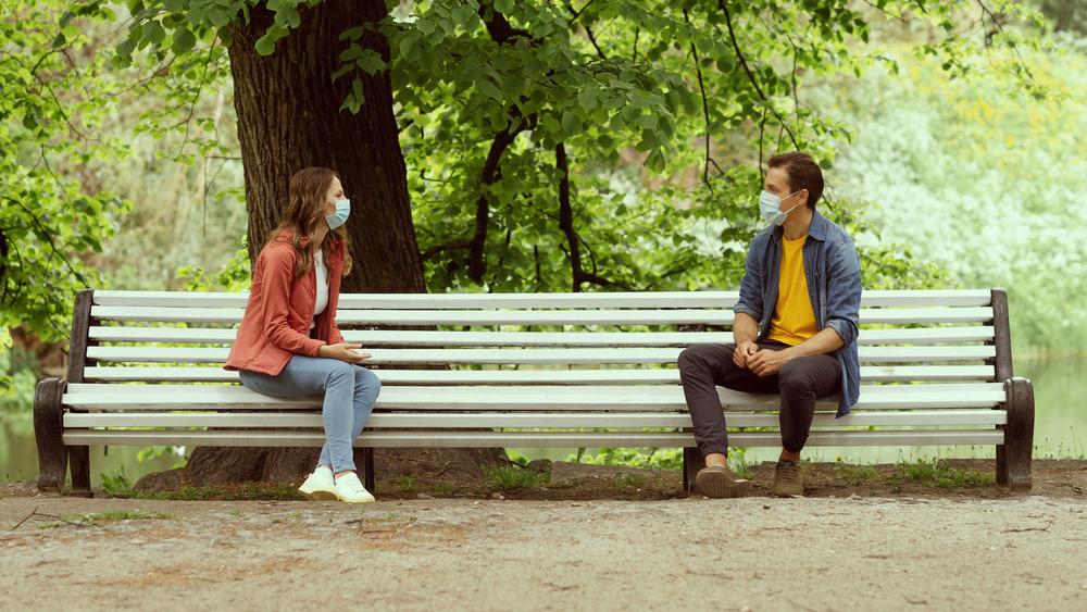 Couple wearing masks on a park bench