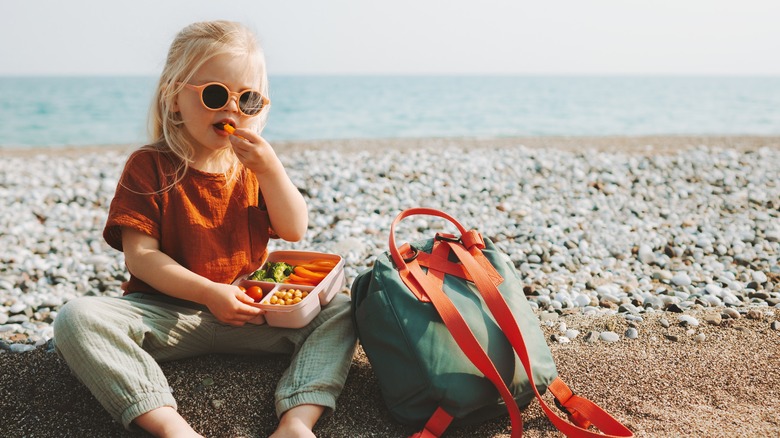 Child eating vegetables on the beach