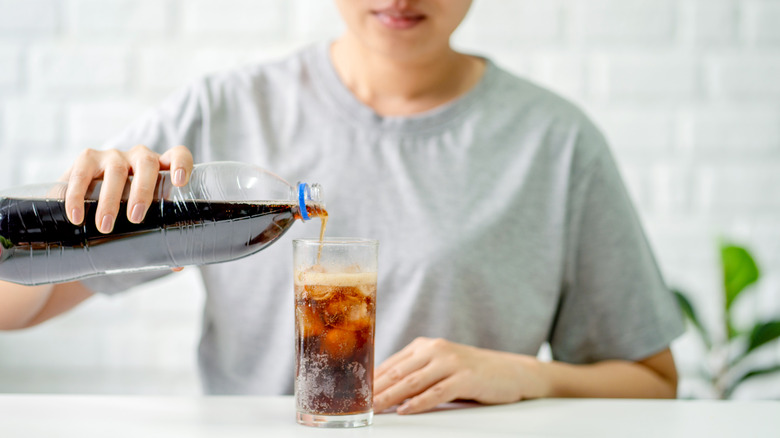 woman pouring glass of cola into cup