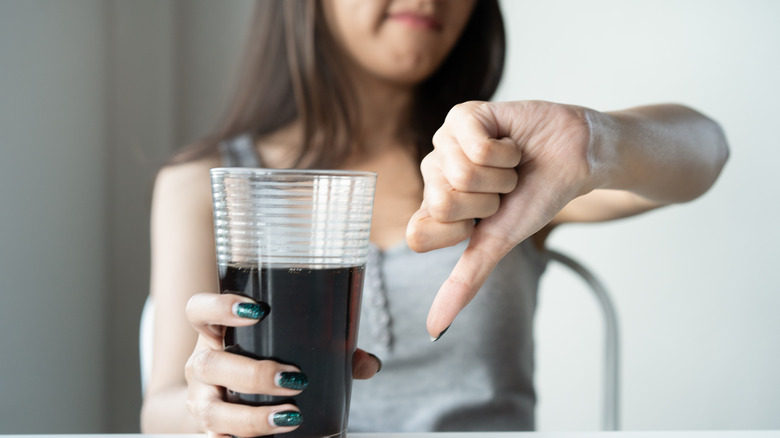 woman thumbs down to soda