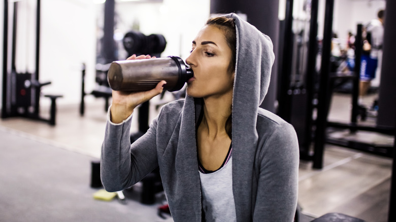 woman drinking protein shake at the gym
