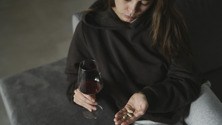 woman drinking wine and taking pills