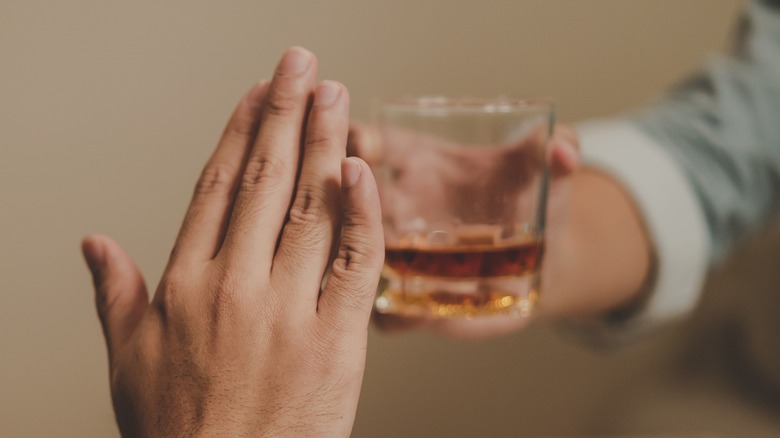 Hand held up to alcohol