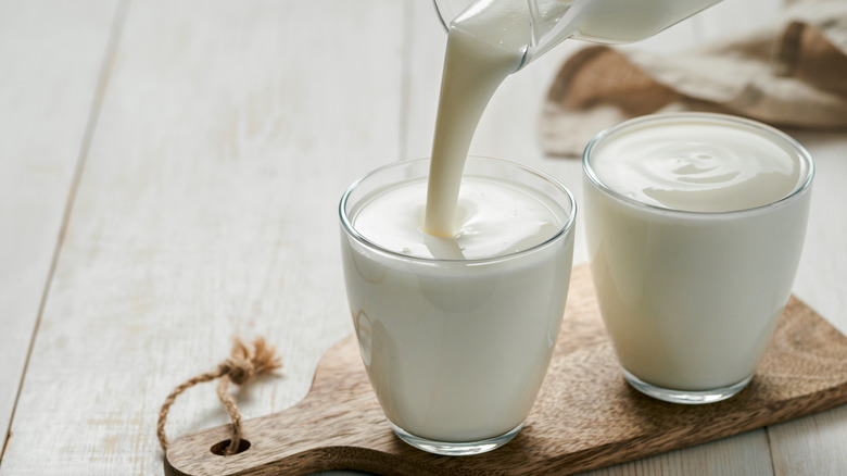 Person pouring milk into two glasses