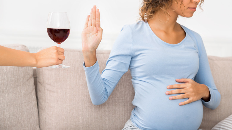 pregnant woman refusing glass of wine