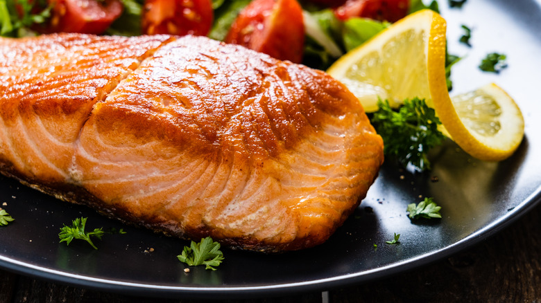 Filet of salmon on plate with lemon slice 