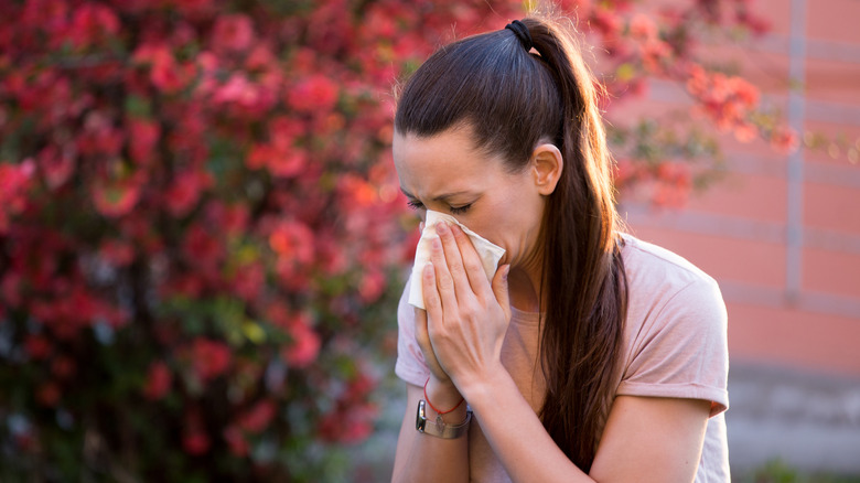 Woman sneezing into a tissue