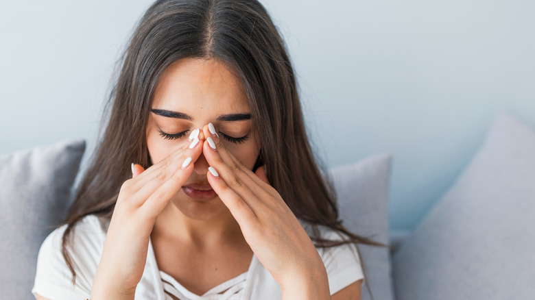 a woman holds her nose in pain