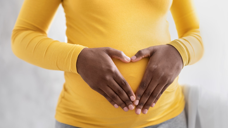 Hands in heart shape on pregnant belly
