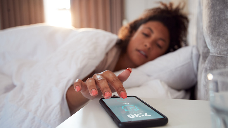 Woman turning off phone alarm